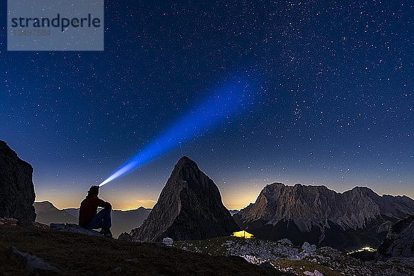 Gipfel der Sonnenspitze mit Bergsteiger und Zelt sowie Zugspitze im Hintergrund mit blauer Stunde und Sternenhimmel  Ehrwald  AuÃŸerfern  Tirol  Ã-sterreich  Europa
