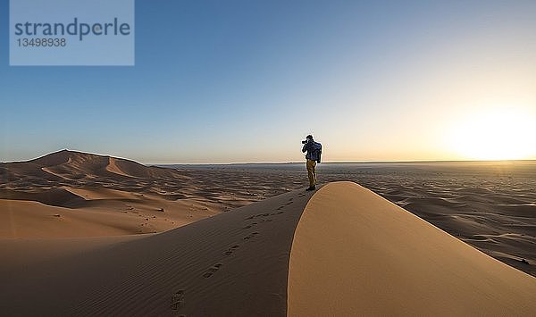 Junger Mann fotografiert  Sanddüne  Sonnenaufgang  Erg Chebbi  Merzouga  Sahara  Marokko  Afrika
