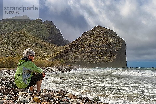 Tourist sitzt am Strand des Parque RubÃ©n Perez vor dem Charco de la Aldea  Los Caserones  Gran Canaria  Spanien  Europa