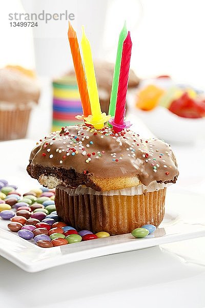 Muffin mit Schokoladenüberzug  Kerzen und farbigen Schokoladentropfen