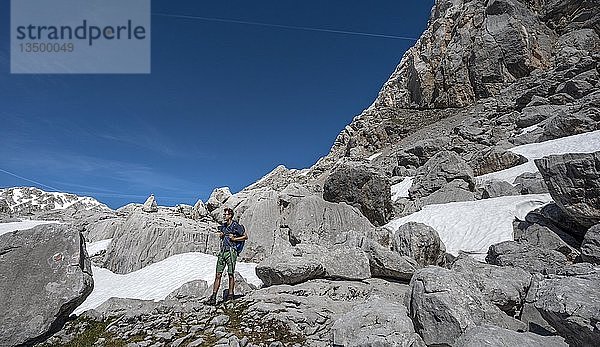 Wanderer zwischen Felsen und Schneeresten  Wanderweg zur Wasseralm über Niederbrunnsulzen  Steinernes Meer  Nationalpark Berchtesgaden  Bayern  Deutschland  Europa