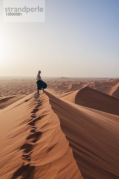 Wanderin auf einer roten Sanddüne in der Wüste  Dünenlandschaft Erg Chebbi  Merzouga  Sahara  Marokko  Afrika