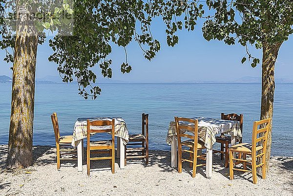 Tische und Stühle einer Taverne direkt am Wasser  Küste  Boukari  Insel Korfu  Ionische Inseln  Griechenland  Europa