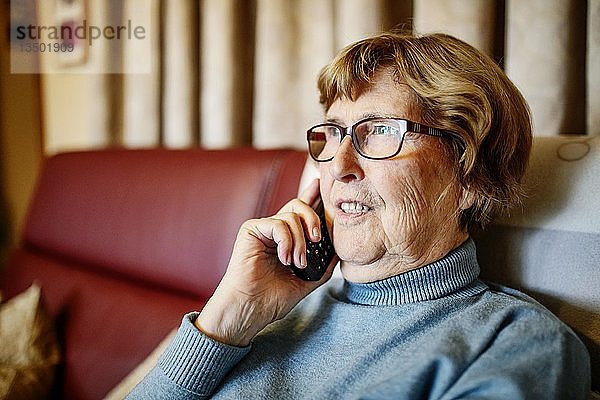 Seniorin telefoniert in ihrem Wohnzimmer  Nordrhein-Westfalen  Deutschland  Europa