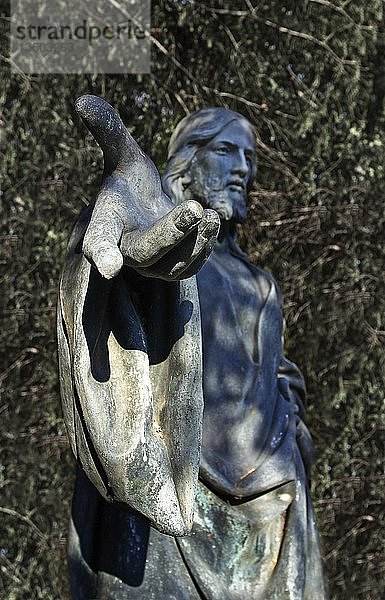 Skulptur von Jesus Christus vor einem Busch