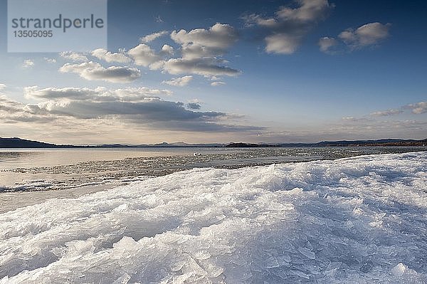 Sonnenlicht mit stimmungsvollen Wolken  gestapelte Eisschollen am Ufer der Insel Reichenau  Baden-Württemberg  Deutschland  Europa