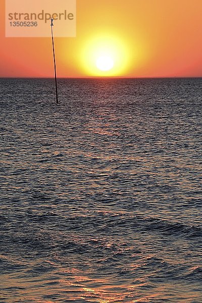 Untergehende Sonne über der Nordsee neben einem Seezeichen  Amrum  Nordfriesische Insel  Nordfriesland  Schleswig-Holstein  Deutschland  Europa