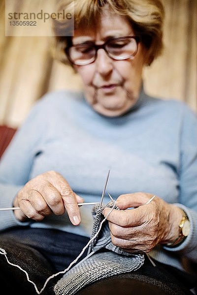 Seniorin strickt zu Hause auf dem Sofa einen Strumpf  Nordrhein-Westfalen  Deutschland  Europa