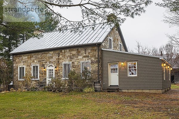 Alte Hausfassade im Landhausstil von 1820 aus behauenen Steinen und Feldsteinen mit Zedernschindeln als Anbau im Herbst  Quebec  Kanada  Nordamerika