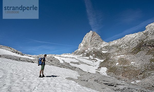Wanderer auf Schneefeld  Wanderweg zur Wasseralm über Niederbrunnsulzen  hinter WIldalmrotenkopf  Steinernes Meer im Frühling mit Schnee  Nationalpark Berchtesgaden  Bayern  Deutschland  Europa