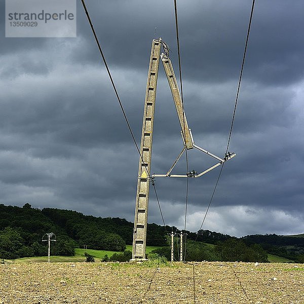 Vom Sturm zerbrochener Strommast aus Beton auf einem Feld auf dem Lande  stürmischer Himmel  Auvergne  Frankreich  Europa