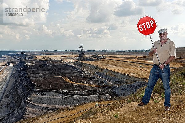 Mann steht am Rande eines Tagebaus und hält ein Stoppschild hoch  Grevenbroich  Nordrhein-Westfalen  Deutschland  Europa