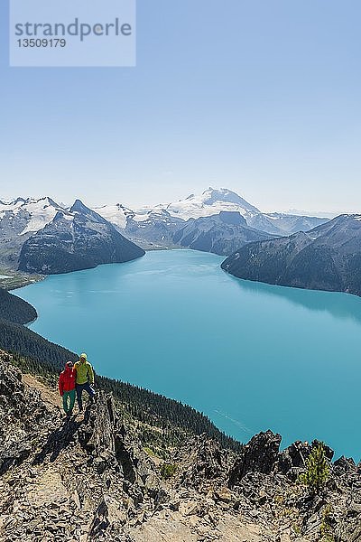 Blick vom Panorama Ridge Trail  zwei Wanderer auf einem Felsen  Garibaldi Lake  türkisfarbener Gletschersee  Guard Mountain und Deception Peak  Hintergletscher  Garibaldi Provincial Park  British Columbia  Kanada  Nordamerika
