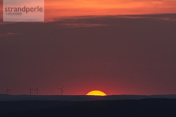 Glühende Sonne und Silhouetten von Windkraftanlagen am Horizont  Sonnenuntergang  Bayern  Deutschland  Europa