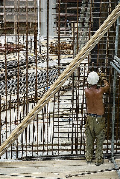 Bauarbeiter mit nacktem Oberkörper beim Verbinden von Stahlmatten  Vorbereitung für das Gießen von Zement  Deutschland  Europa