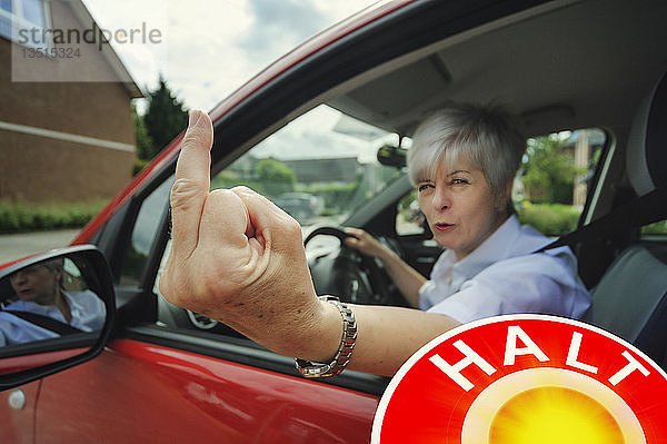 Autofahrerin macht eine unhöfliche Handbewegung während einer Verkehrskontrolle  Grevenbroich  Rheinland  Nordrhein-Westfalen  Deutschland  Europa
