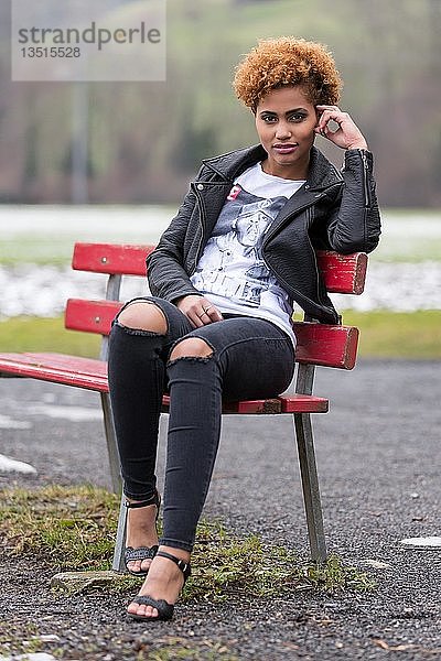 Junge dunkle Frau auf einer Bank sitzend  Mode