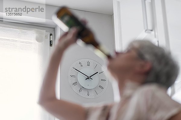 Alkoholabhängige Frau  Alkoholikerin  trinkt am helllichten Tag eine Flasche Bier