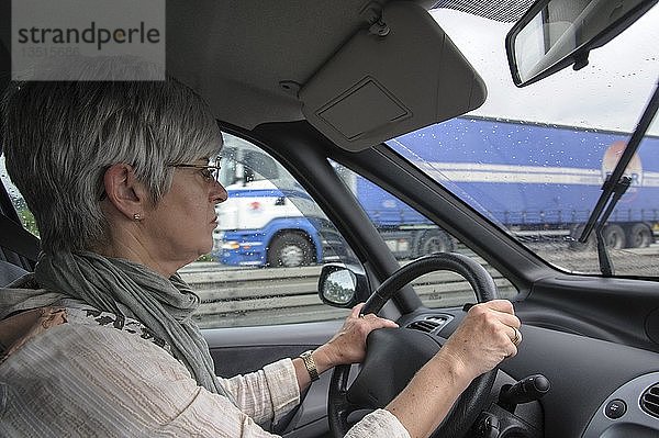 Frau sitzt hinter dem Lenkrad eines Autos  sie fährt auf der Autobahn  Niedersachsen  Deutschland  Europa