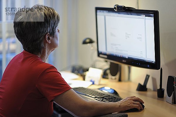 Frau sitzt an einem Schreibtisch und arbeitet an einem PC
