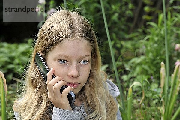 9-jähriges Mädchen mit Handy  Mobiltelefon im Garten