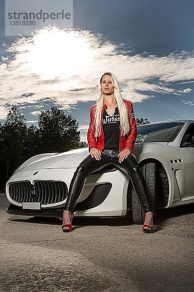 Junge Frau mit langen blonden Haaren posiert mit weißem Maserati Gran Turismo MC Stradale