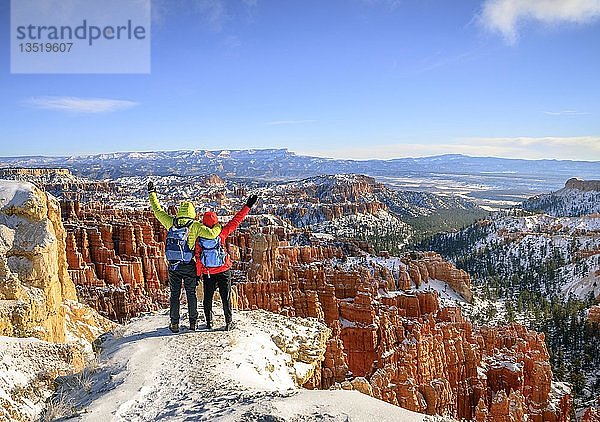 Touristen mit ausgestreckten Armen mit Blick auf das Amphitheater  bizarre schneebedeckte Felslandschaft mit Hoodoos im Winter  Rim Trail  Bryce Canyon National Park  Utah  USA  Nordamerika