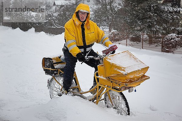 Mann  Briefträger  Briefträger auf gelbem Postfahrrad bei winterlichen Bedingungen  Bayern  Deutschland  Europa