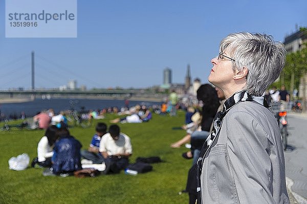 Frau genießt die Frühlingssonne auf den Rheinwiesen  Düsseldorf  Nordrhein-Westfalen  Deutschland  Europa