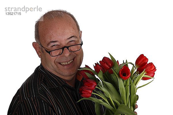 Lachende Rentnerin mit Brille und Tulpen in der Hand