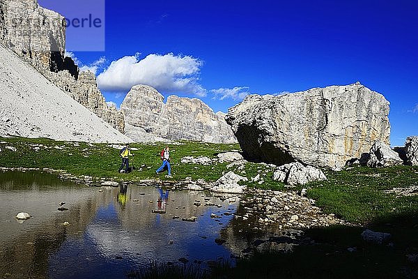 Wanderer unterhalb des Paternsattels spiegeln sich in einer Pfütze  Weg 101  hinter dem Gipfel des Einser  Sextner Dolomiten  Hochpustertal  Südtirol  Italien  Europa