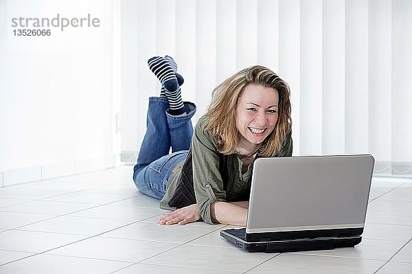 Junge Frau mit einem Laptop auf dem Boden