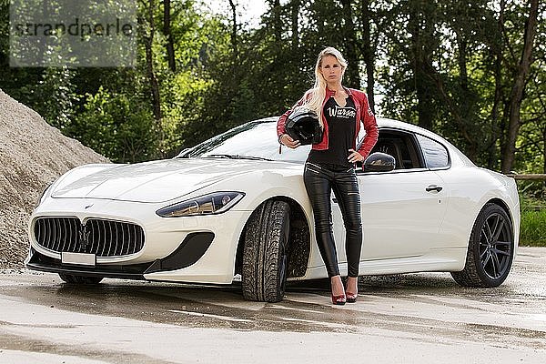 Junge Frau mit langen blonden Haaren posiert mit weißem Maserati Gran Turismo MC Stradale