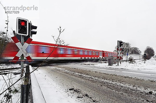 Personenzug beim Passieren eines Bahnübergangs im Winter  Grevenbroich  Nordrhein-Westfalen  Deutschland  Europa