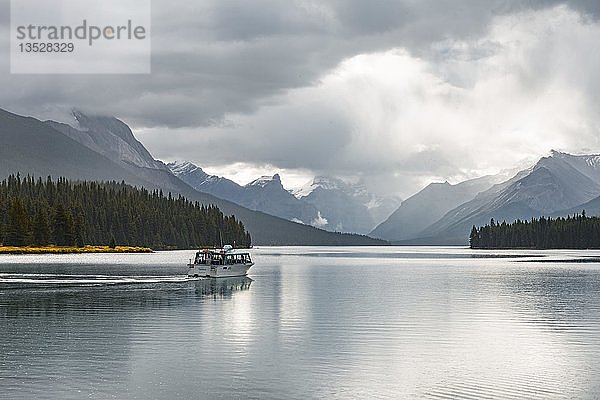 Ausflugsboot mit Touristen auf dem Maligne Lake  dahinter Bergkette Queen Elizabeth Ranges  bewölkter Himmel  Jasper National Park  Rocky Mountains  Alberta  Kanada  Nordamerika