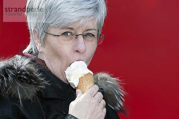 Frau isst Eiscreme vor einer roten Wand