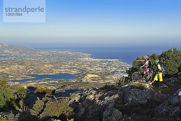 Zwei Mountainbiker stehen auf einem Aussichtspunkt mit Blick auf Lerapetra  bei Stavros  Selakano  Kreta  Griechenland  Europa