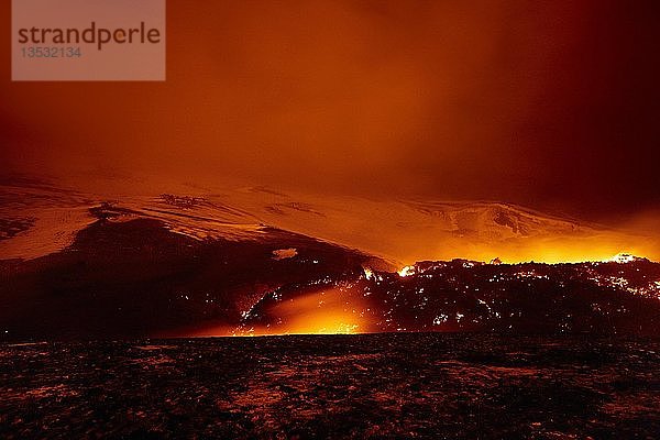 Glühende Lava und Lavastrom bei Nacht auf dem Vulkan Fimmvörðuháls  Spaltausbruch auf dem Fimmvörduhals  hinter dem Eyjafjallajökull-Gletscher  Hochland  Island  Europa