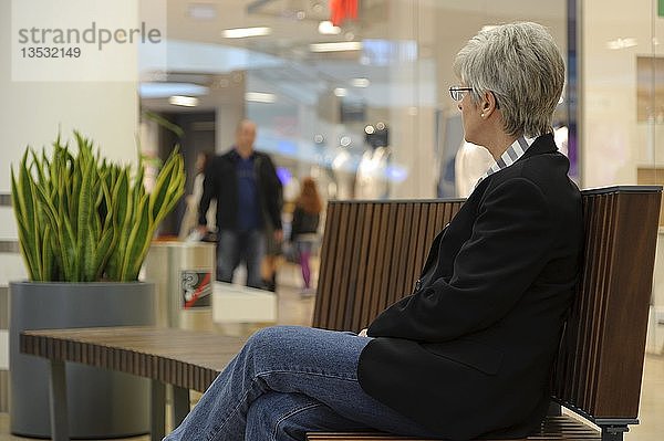 Frau sitzt auf einer Bank und beobachtet einen Mann