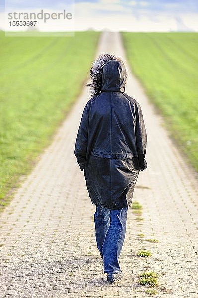 Frau geht auf einem Feldweg  von hinten  Grevenbroich  Nordrhein-Westfalen  Deutschland  Europa