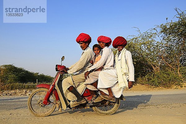 Vier Männer aus drei Generationen fahren gemeinsam auf einem Motorrad  Rajasthan  Indien  Asien