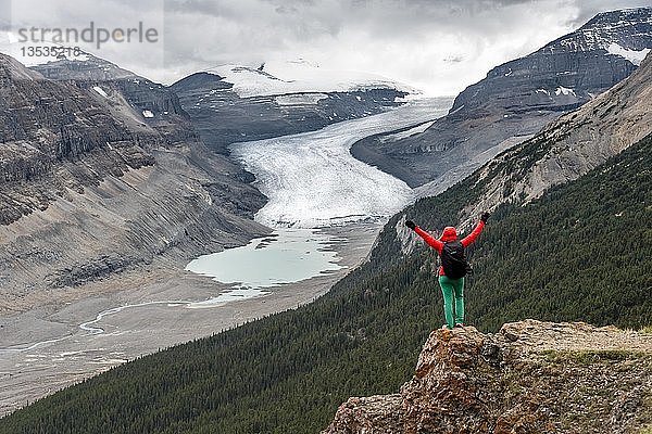 Wanderer steht auf einem Felsen  streckt die Arme in die Luft  Blick ins Tal mit Gletscherzunge  Parker Ridge  Saskatchewan Glacier  Athabasca Glacier  Jasper National Park National Park  Canadian Rocky Mountains  Alberta  Kanada  Nordamerika