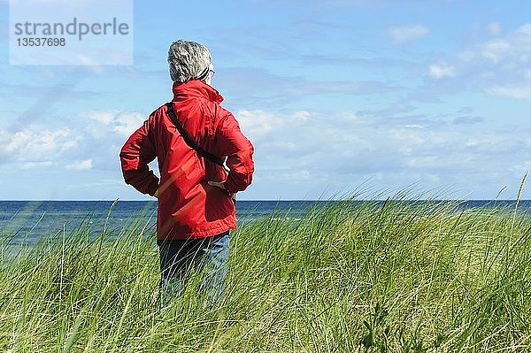 Eine Frau  die in den Dünen steht und auf das Meer hinausschaut  Insel Poel  Mecklenburg-Vorpommern  Deutschland  Europa