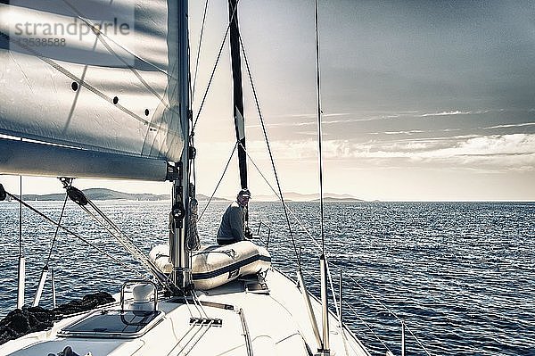 Skipper sitzt am Bug seiner Segelyacht und schaut nach achtern  Adriatisches Meer  Kroatien  Europa