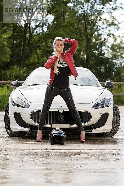 Junge Frau mit langen blonden Haaren posiert mit weißem Maserati Gran Turismo MC Stradale