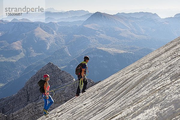 Bergführer führt eine junge Frau an einem kurzen Seil durch eine Felswand  Wiederroute  Watzmann  Schönau am Königsee  Berchtesgadener Land  Bayern  Deutschland  Europa