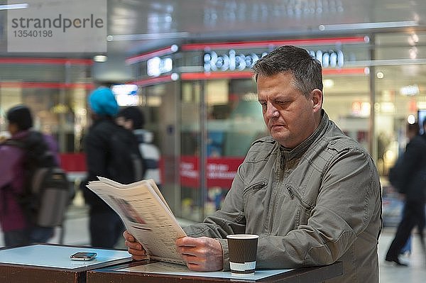 Mann steht in einem Einkaufszentrum und liest eine Zeitung  Düsseldorf  Nordrhein-Westfalen  Deutschland  Europa