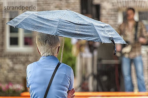 Eine ältere Frau hält einen Regenschirm  Paffendorf  Nordrhein-Westfalen  Deutschland  Europa