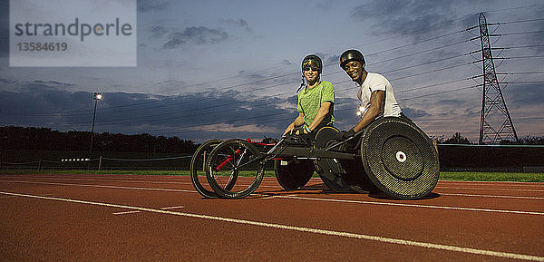 Porträt selbstbewusster  querschnittsgelähmter Sportler auf einer Sportbahn  der nachts für ein Rollstuhlrennen trainiert