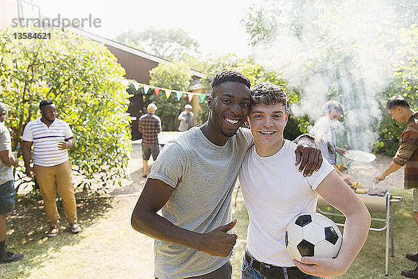 Porträt selbstbewusster junger Mann mit Fußball beim Grillen im Hinterhof